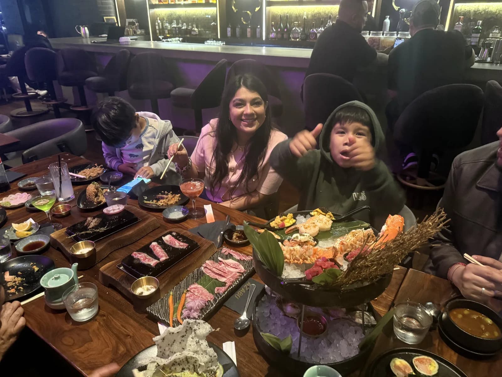 Family at Azabu giving a thumbs-up over the Premium Seafood Tower and platters of Wagyu