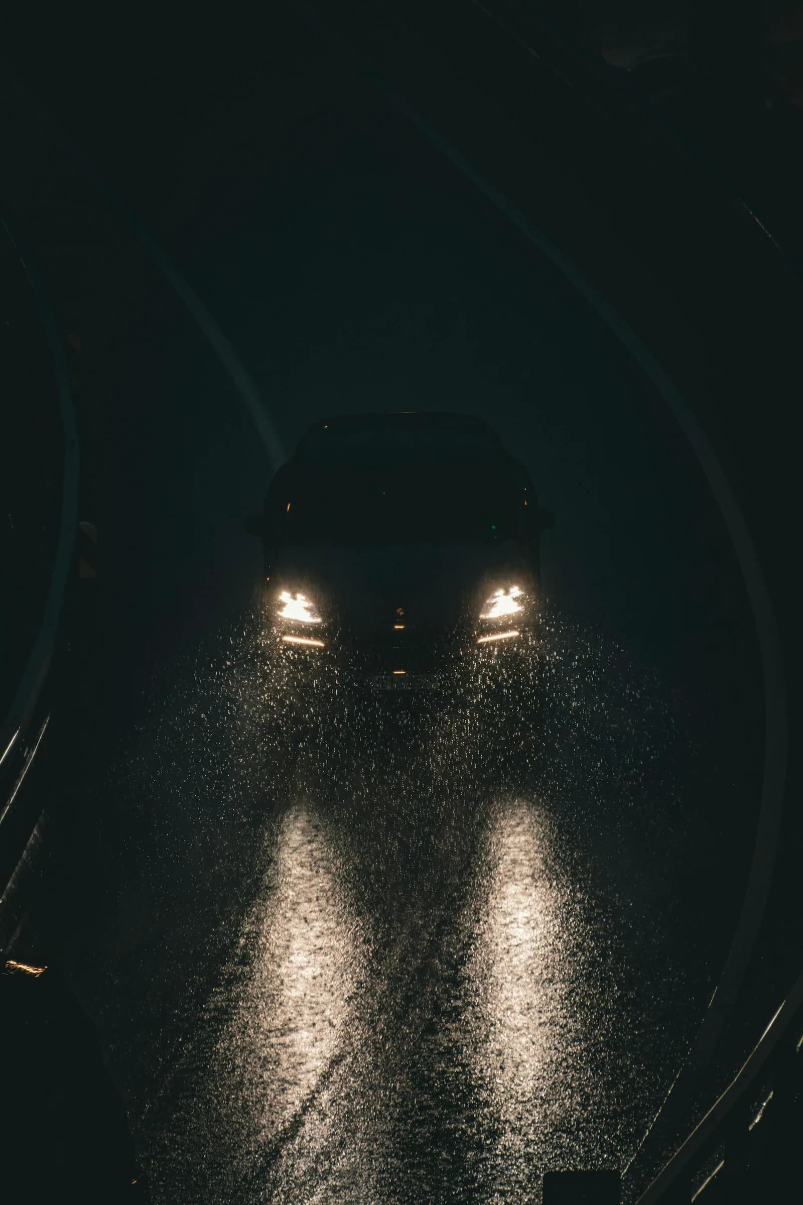 Faros de un auto en una carretera mojada de noche bajo la lluvia