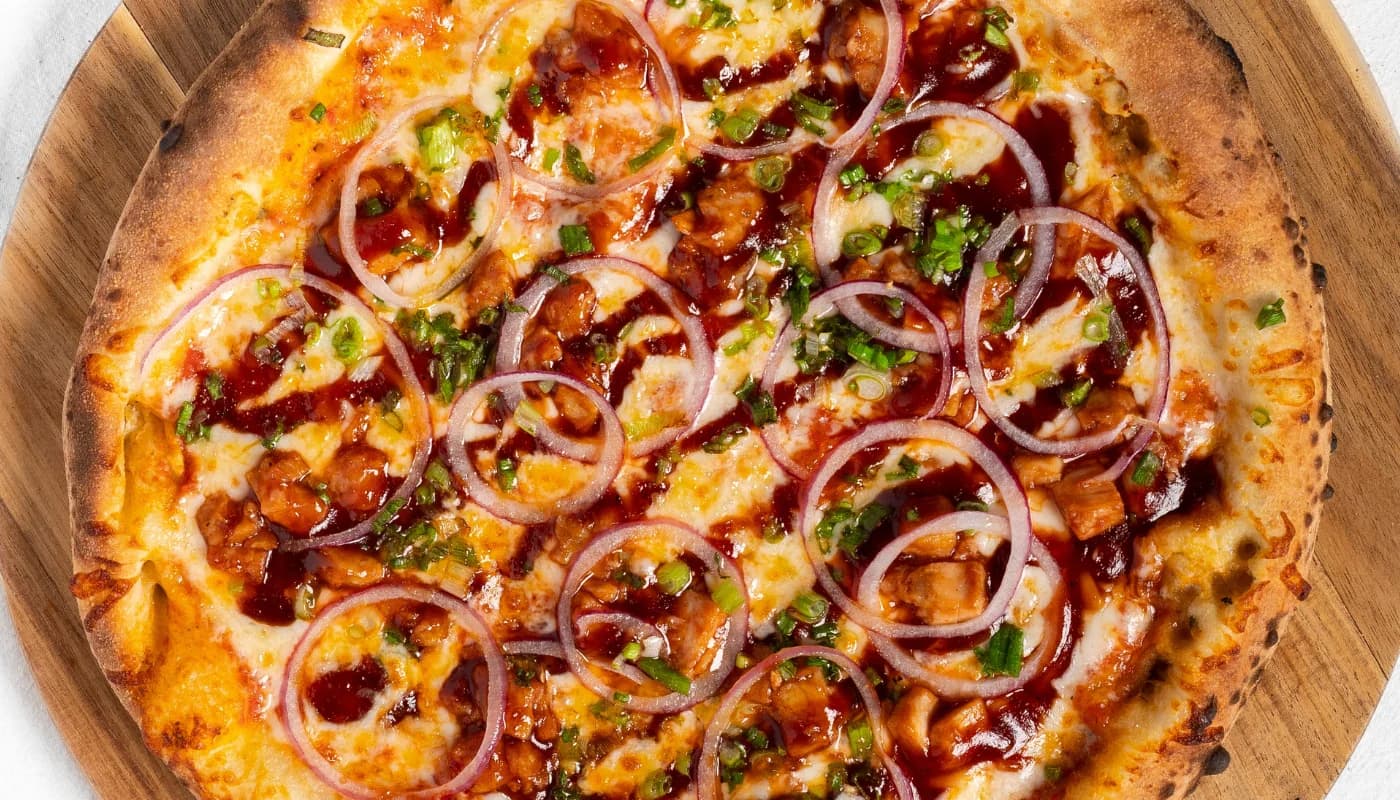 Pizza de pollo BBQ con cebolla morada y cebollín